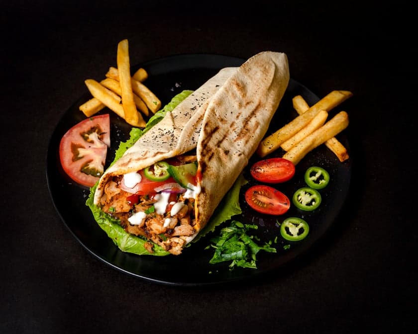 Chicken shawarma carved off the vertical spit, wrapped in lavash with pickles and garlic sauce, Patar Shawarma Glendale
