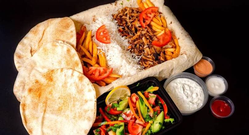 Crispy fries loaded with carved shawarma, garlic sauce, pickled turnips, and onion in a bowl at Patar Shawarma Glendale